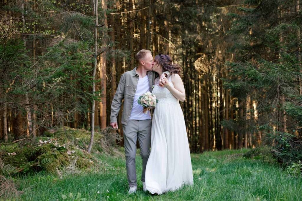 Brautpaar im Wald bei Sonnenlicht, romantisches Hochzeitsfoto.