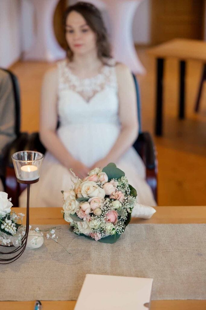 Emotionale Hochzeitsaufnahme mit Braut, Blumen und Kerzen im Hintergrund.