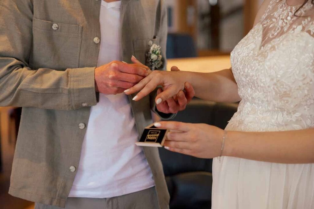 Paar bei Hochzeit tauscht Ringe während Zeremonie.