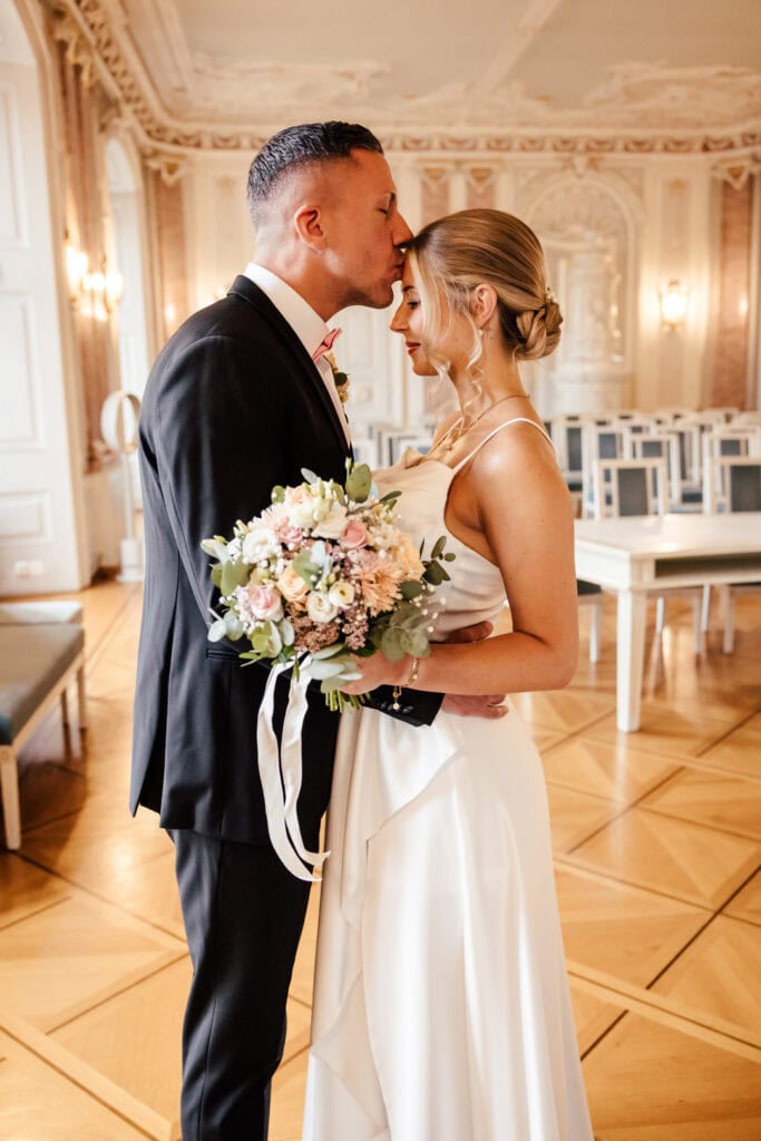 Braut und Bräutigam küssen sich im festlichen Saal.