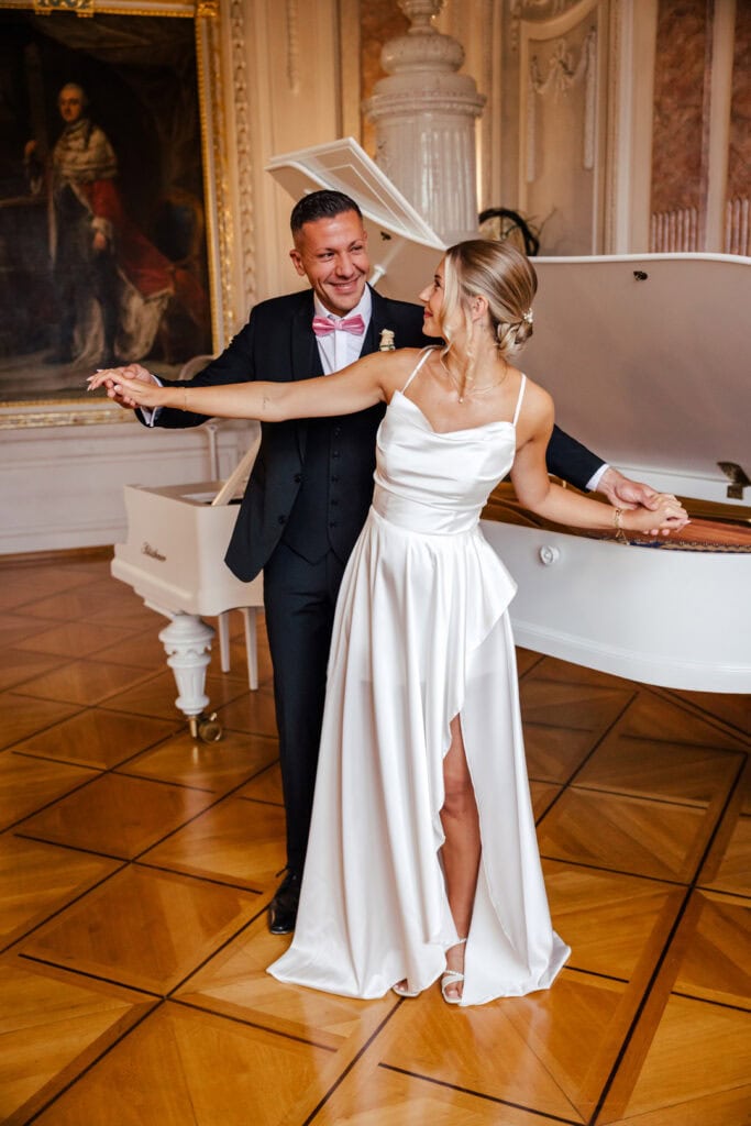 Braut und Bräutigam tanzen elegant im Schloss Saal.