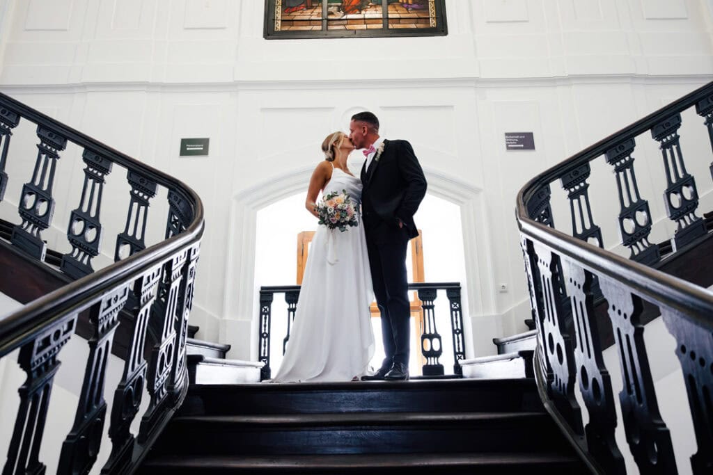 Braut und Bräutigam küssen sich auf Treppe bei Hochzeit in Lauingen.