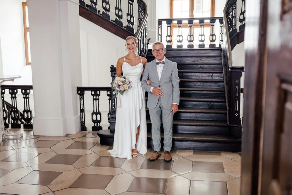 Braut und Bräutigam vor Treppe im Schloss, fotografiert von Saskia Römer – Fotografie mit Herz Laung.