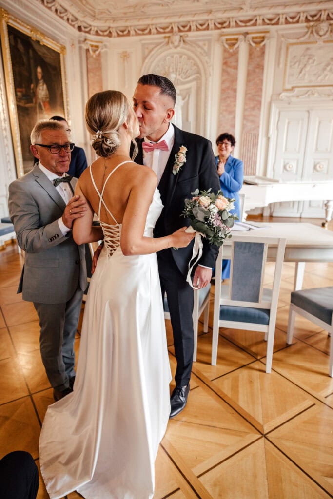 Braut und Bräutigam küssen sich im eleganten Saal, fotografiert von Saskia Römer – Fotografie mit ❤️.