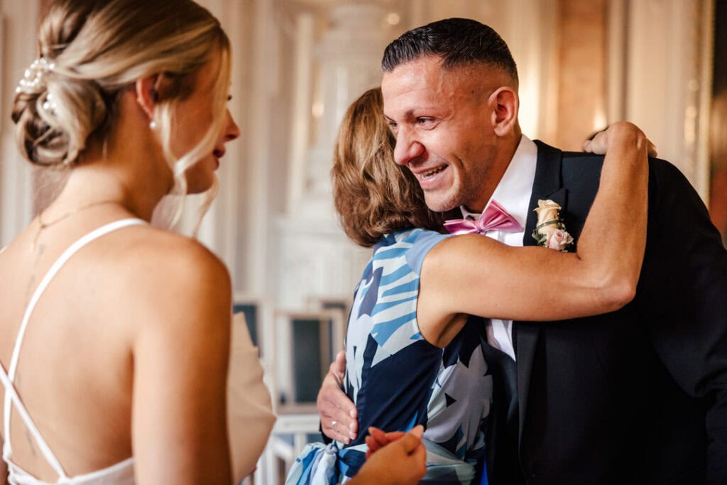 Glückliches Brautpaar umarmt eine Frau bei Hochzeit in Lauingen.