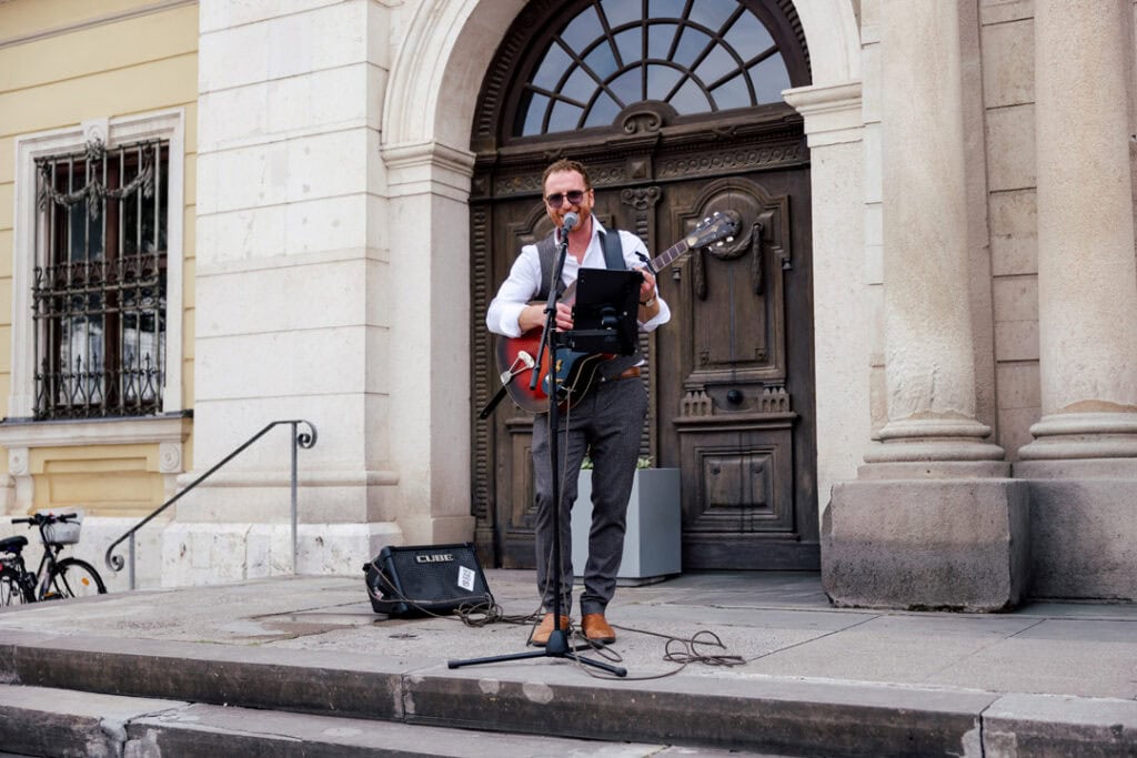 Straßenmusiker mit Gitarre vor historischem Gebäude in Lauingen.